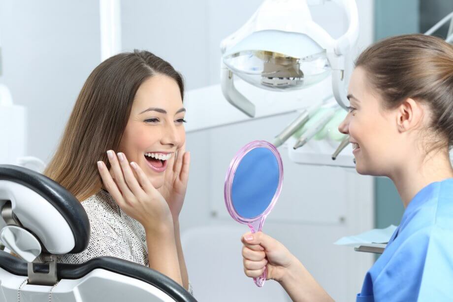 A Woman with Long, Straight Brown Hair Admiring Her New Smile in Dental Office