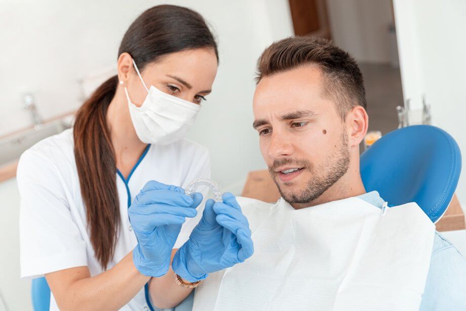 dentist demonstrates Invisalign aligner tray to patient