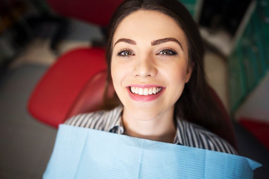 female patient smiles up from dental chair