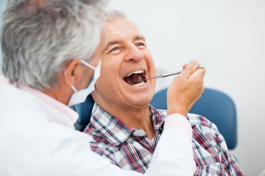 dentist examines the teeth of a mature male patient