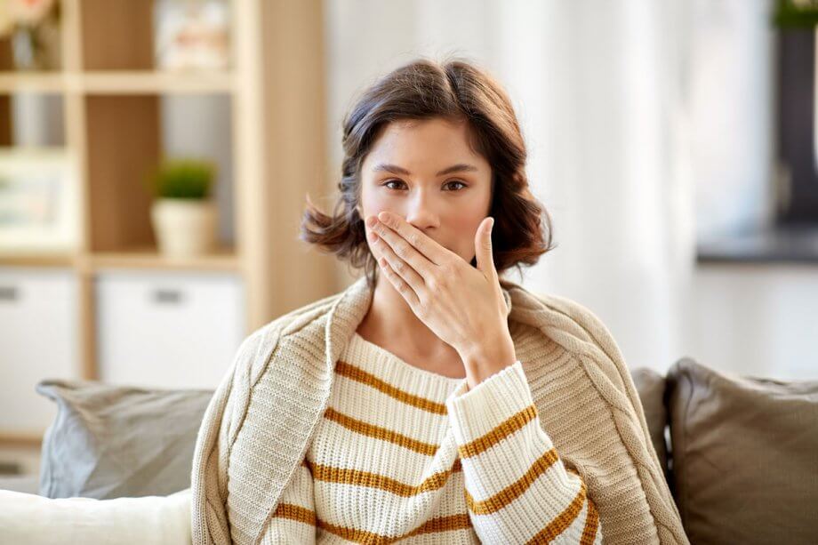 woman holding hand over mouth due to bad breath